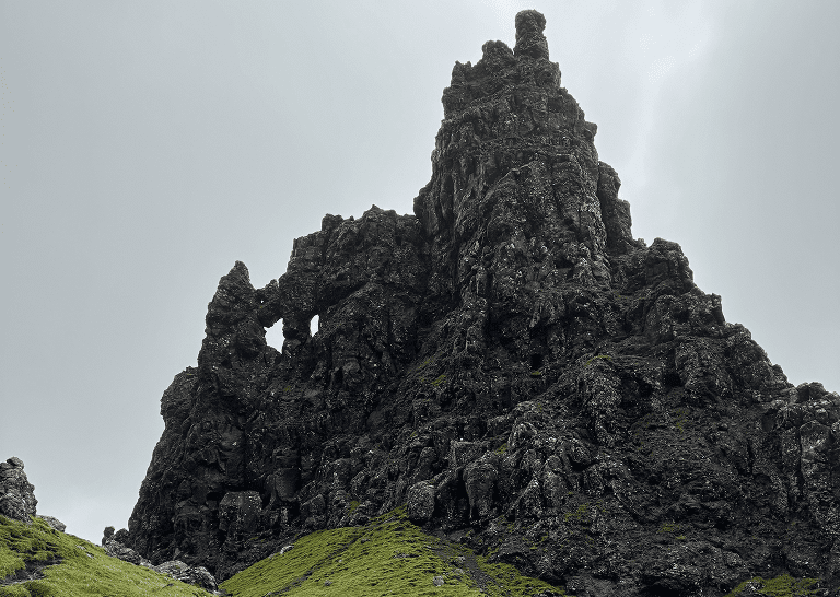 A towering jagged rock formation against a cloudy sky.